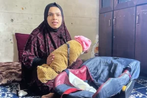 Raeda al-Masry holds her son as she recounts fleeing to Jabalia refugee camp and giving birth in a school without help